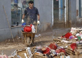 Un hombre saca basura de un local en Alfafar.