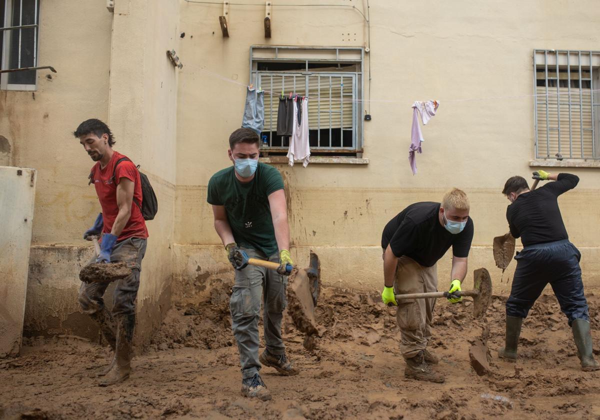 Voluntarios retiran barro con palas.