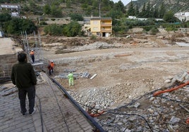 Un hombre observa los trabajos en el puente, con la zona de arboleda del río completamente arrasada.