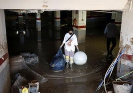 Una vecina retira trastos de un aparcamiento todavía inundado.