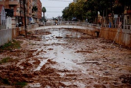 Una persona cruza el barranco de La Saleta que se desbordó recientemente debido a las fuertes lluvias en Aldaia.