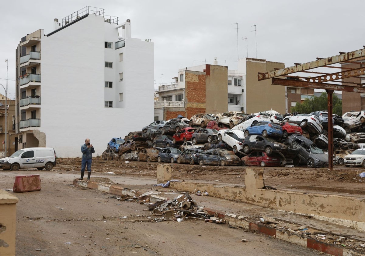 Un hombre ante un depósito con decenas de coches amontonados.