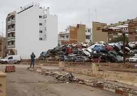 Un hombre ante un depósito con decenas de coches amontonados.