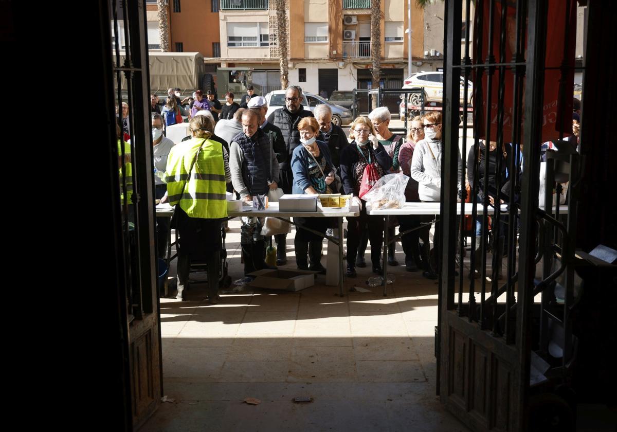 Un grupo de afectados por la DANA espera para recoger la comida caliente del día.