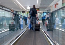 Un pasajero carga con un equipaje de mano en un aeropuerto.