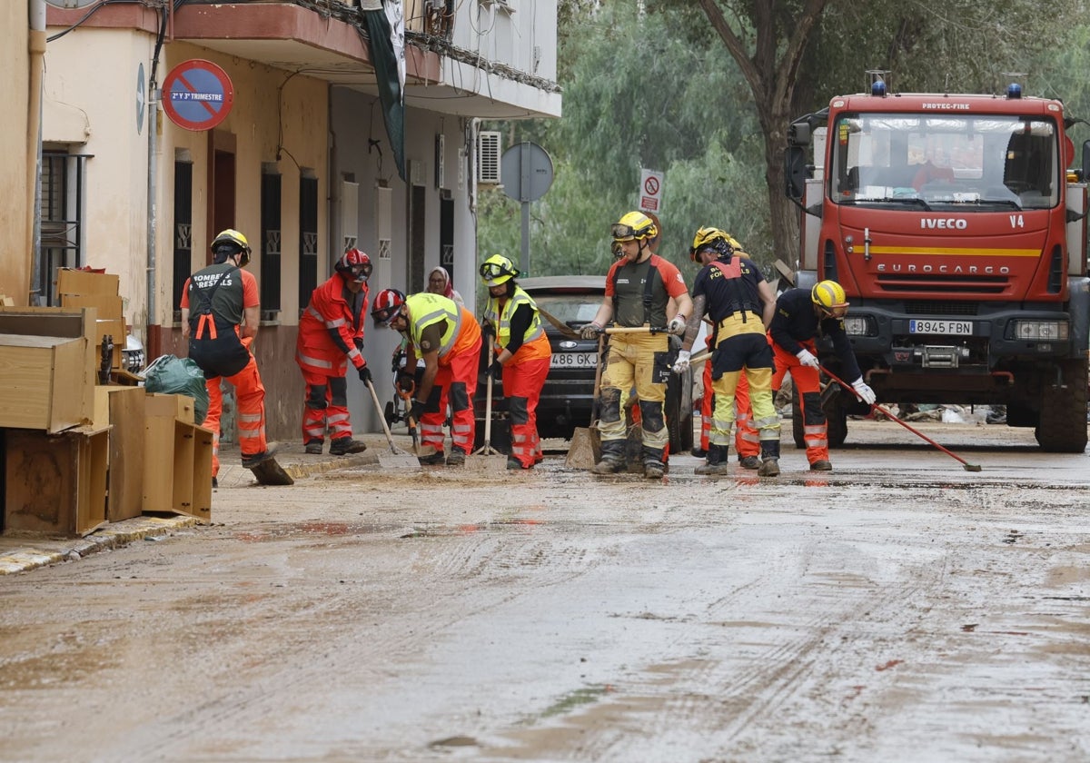 Efectivos de Bomberos limpian una calle de Massanassa.