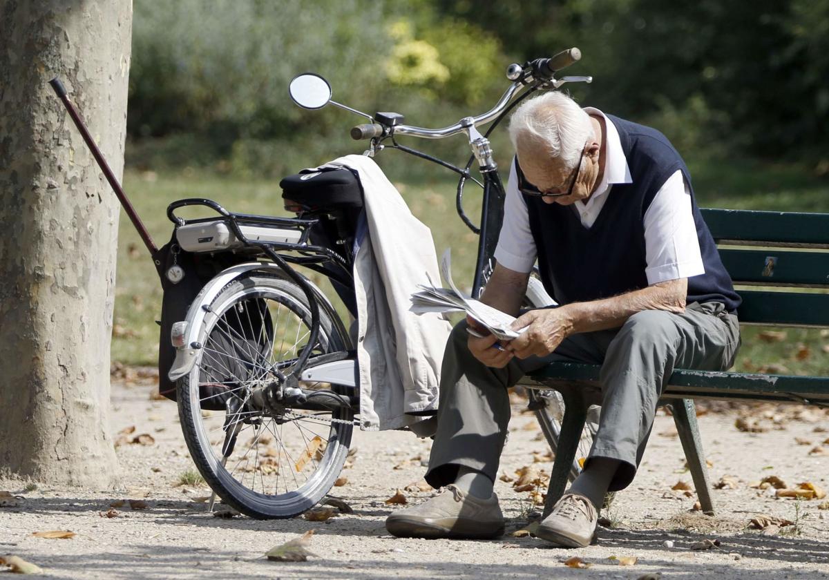 Un jubilado lee el periódico en el parque.