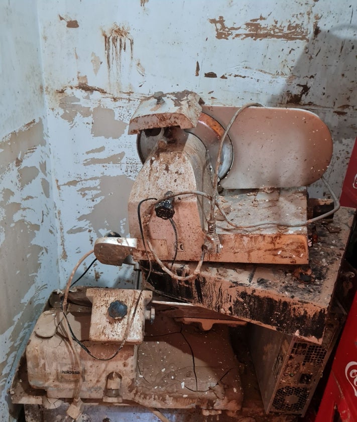 Imagen secundaria 2 - En las dos primera fotos, Edi, de rojo, junto a los voluntarios que le ayudan a hacer la comida y en la inferior el estado del mobiliario de la cocina de su bar tras la barrancada. 