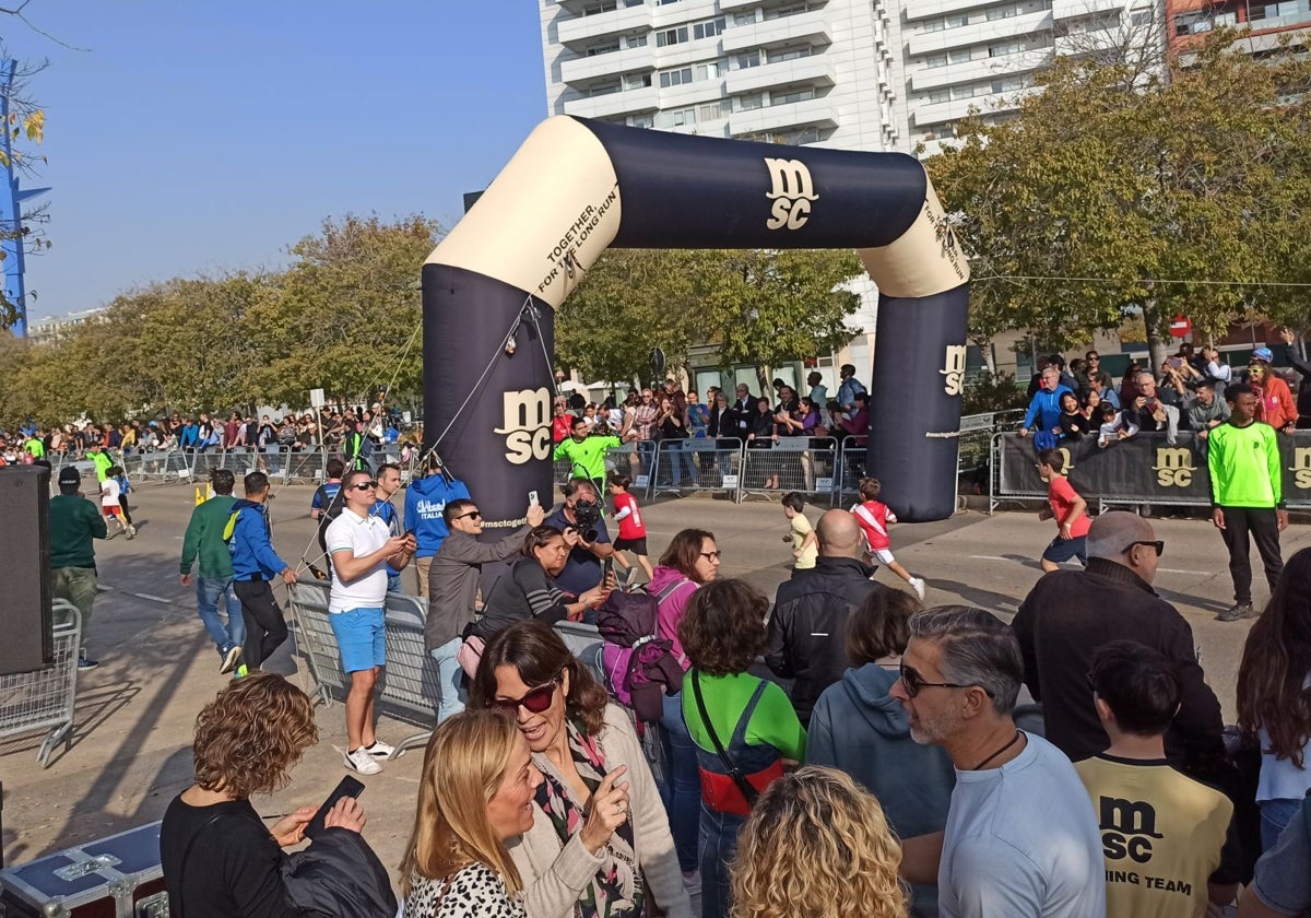 Un grupo de participantes cruza la meta del minimaratón en el Paseo de la Alameda.