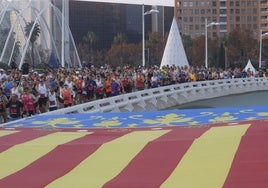 Corredores pasan junto a la enorme Senyera desplegada en el puente de Monteolivete.