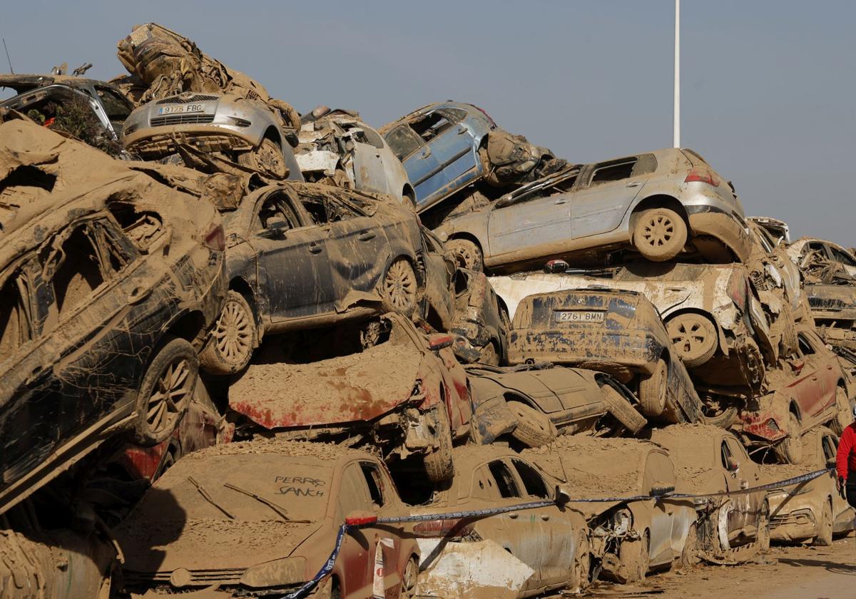 Montaña de coches arrastrados por la riada cubiertos de polvo.