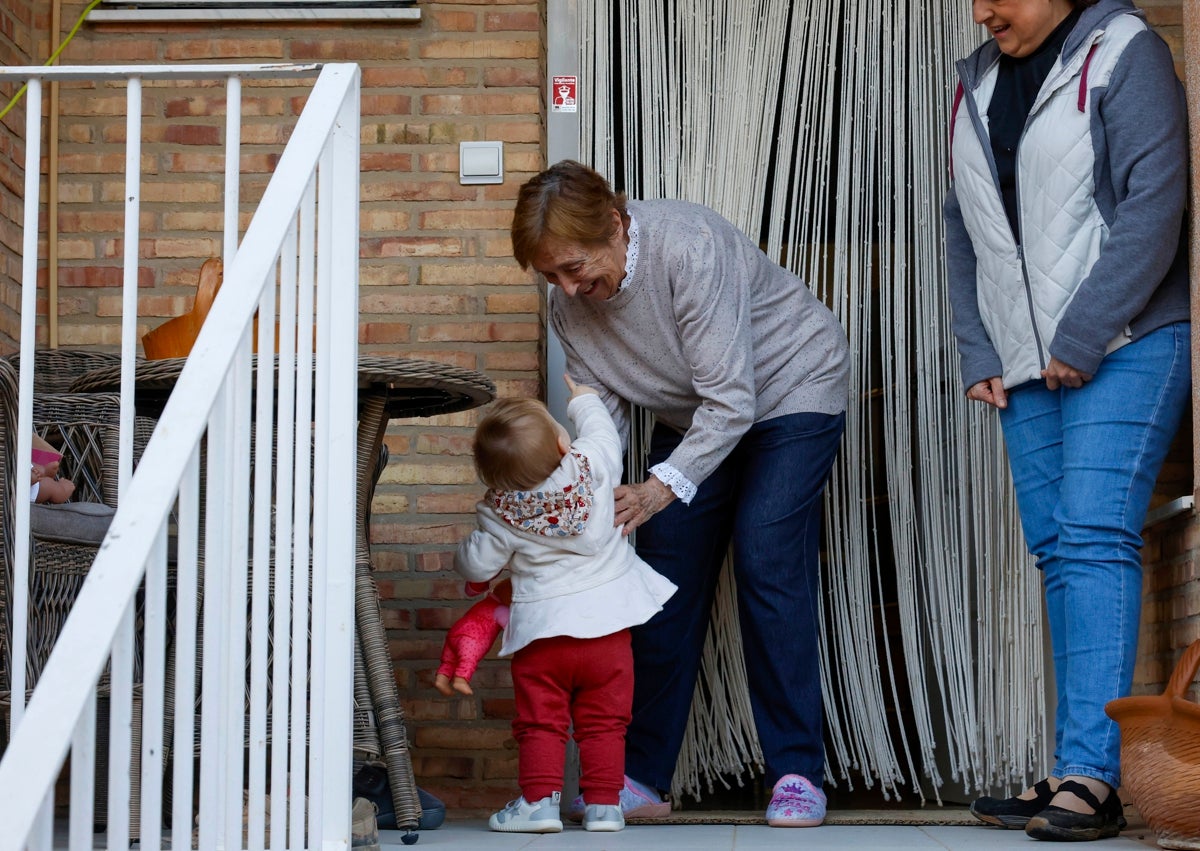 Imagen secundaria 1 - Varias escenas del reportaje: Laia, con sus padres; su bisabuela, Carmen y su abuela Imma.