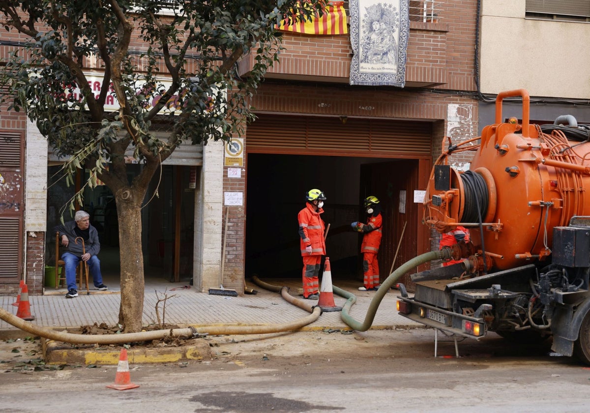 Unos operarios con una cuba a las puertas de un garaje.