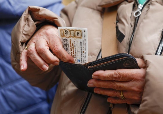 Una mujer guardo su boleto de la Lotería de Navidad en su monedero.