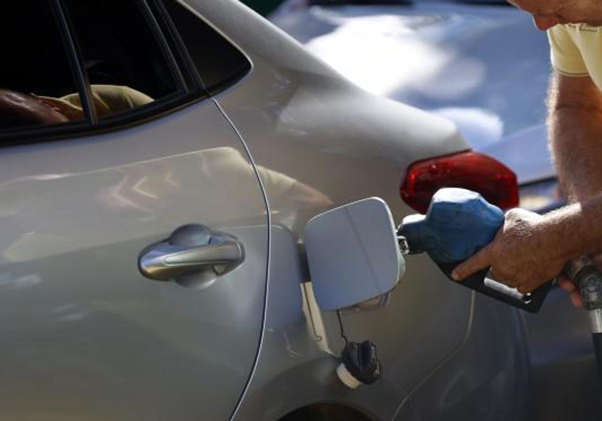 Un conductor llena el déposito de combustible.