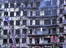 Dos equipos de bomberos en sendas autoescaleras en la fachada del edificio destruido por el fuego en Campanar.