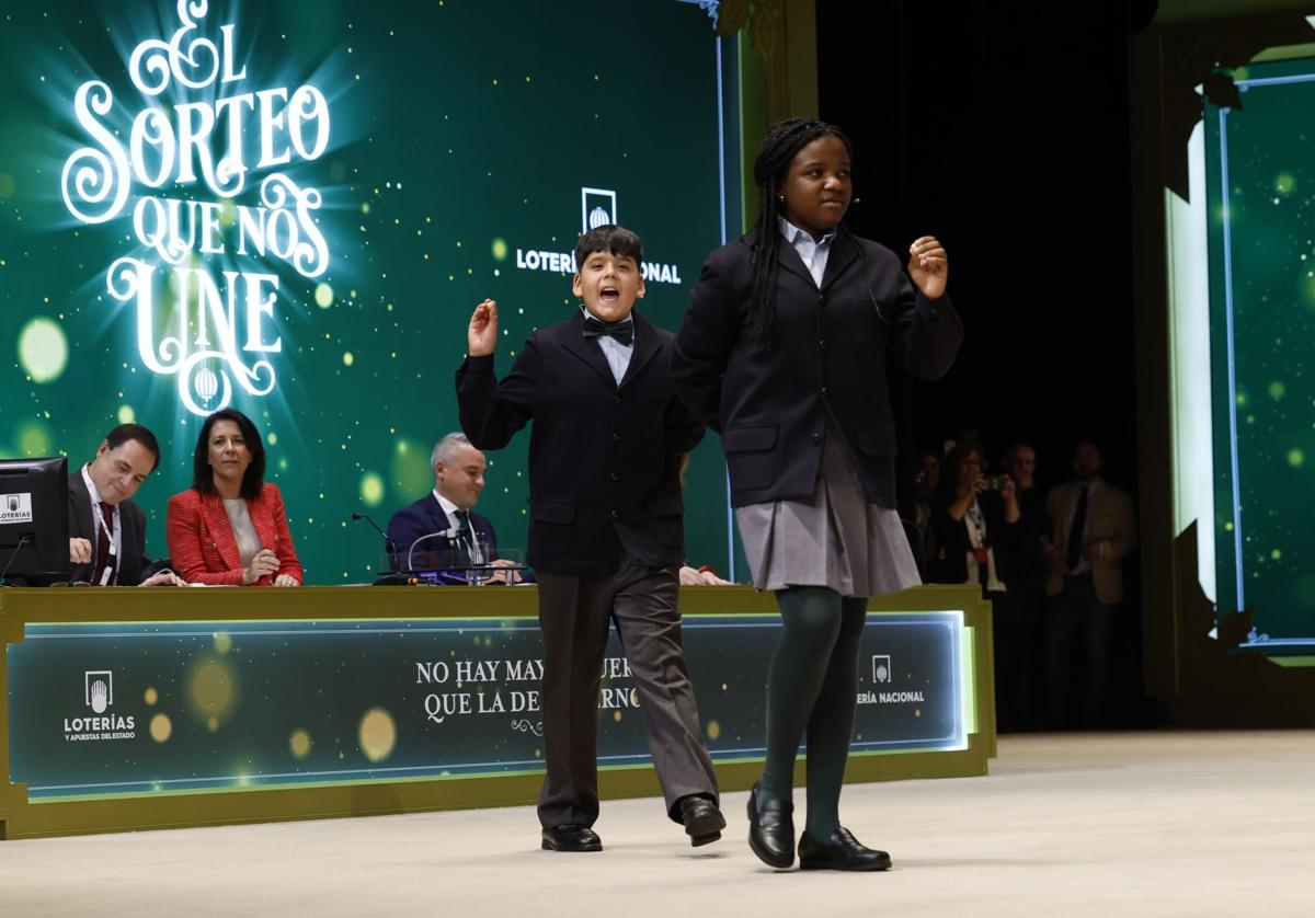 Dos niños de San Idelfonso en el sorteo de 2023 y, tras ellos, los miembros de la mesa.