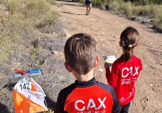 Un niño y una niña tratan de superar el reto de la carrera de la orientación