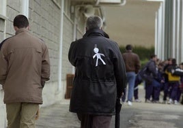 Un hombre camina por la calle con un monigote de papel en la espalda.