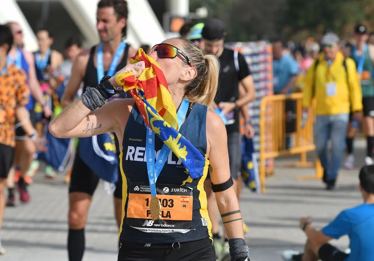 Una corredora del Maratón Valencia besa la Senyera.