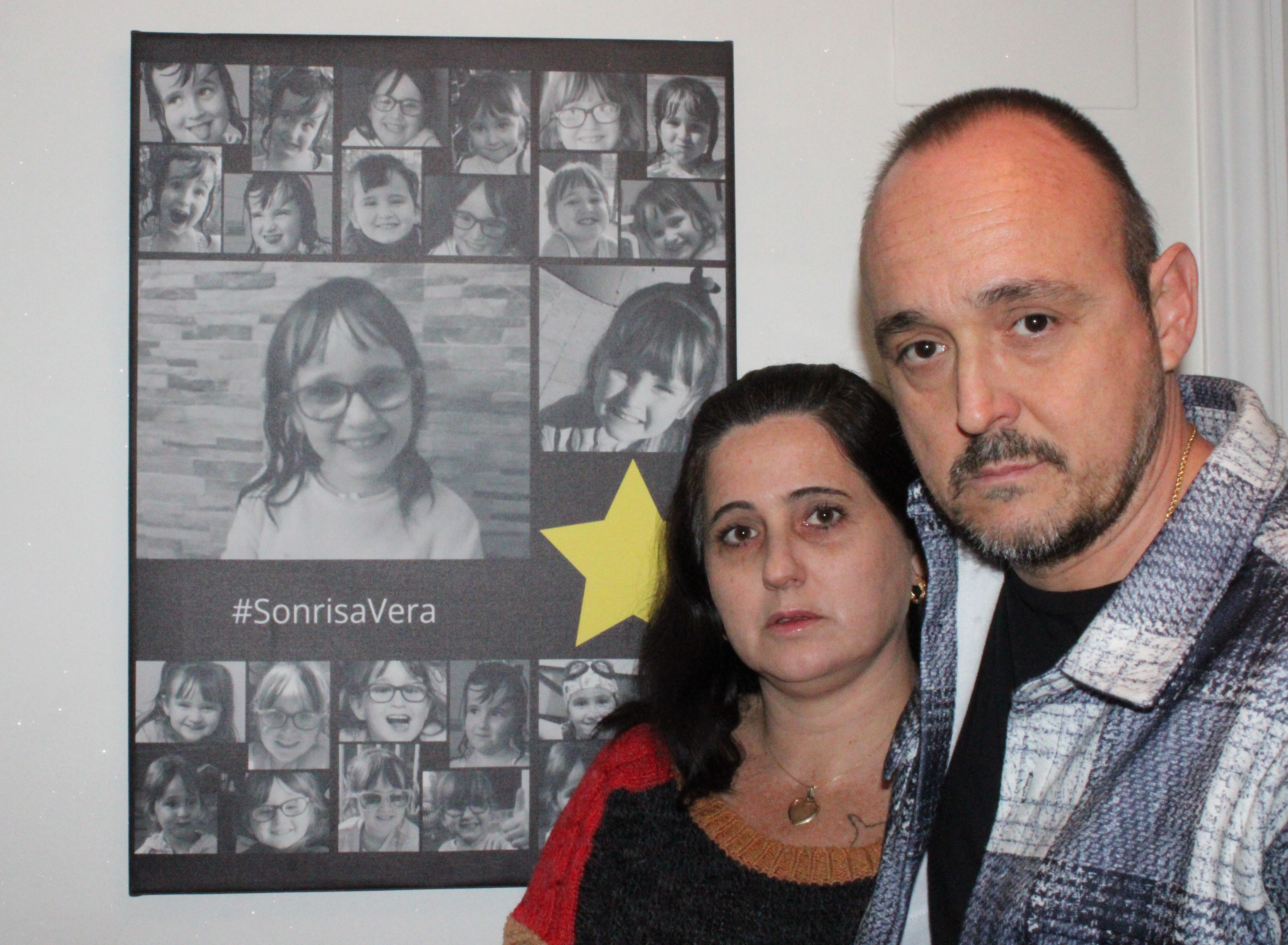 Iván y Eva, los padres de Vera, junto a un mural con fotos de recuerdo de su niña en casa.