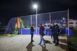 Policías, en el lugar del accidente, con los restos del hinchable sobre la valla de las camas elásticas.