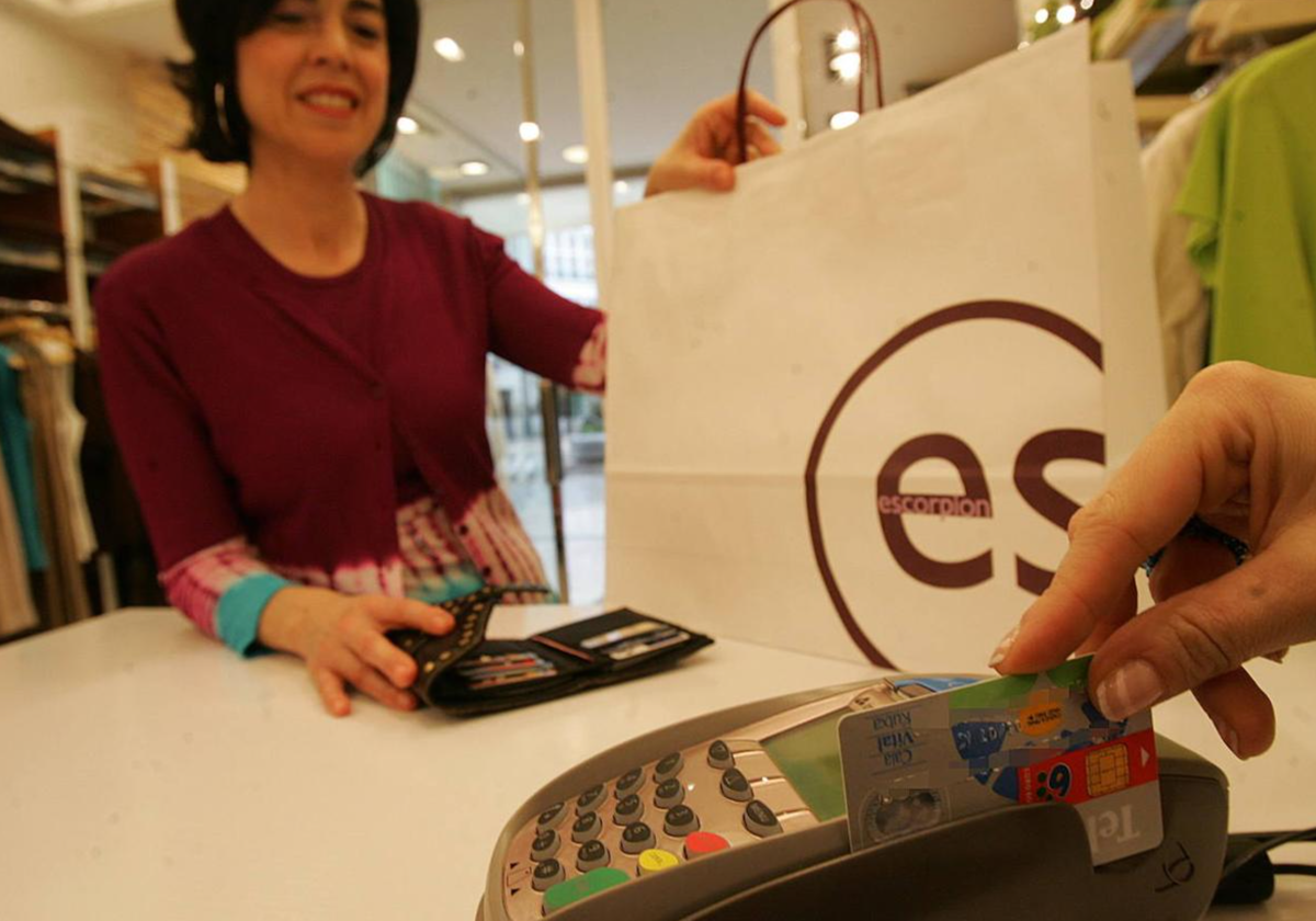 Una mujer paga con tarjeta en un comercio.