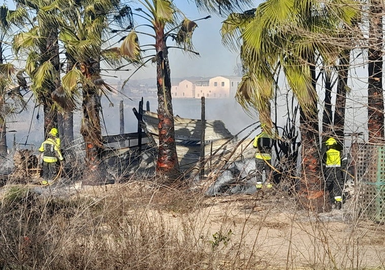 Los bomberos terminan de sofocar el incendio de la caseta.