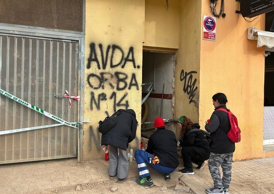 Varias personas colocan velas ante el edificio en el que falleció un trabajador por el derrumbe en Benetússer.