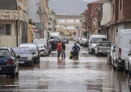 Varias personas inspeccionan los daños en una calle de Llombai.