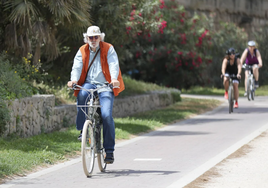 Un mayor circula en bicicleta por el río.