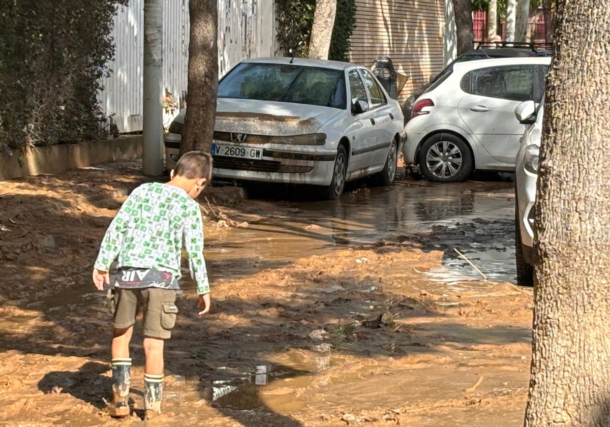 Un niño recorre una calle llena de barro en Picanya, tras la dana.