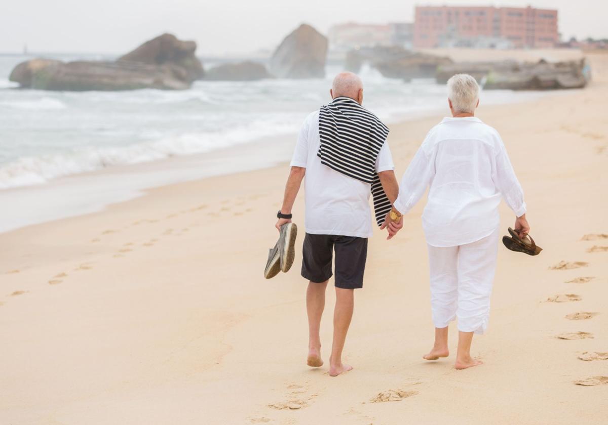 Dos jubilados paseando por la playa.