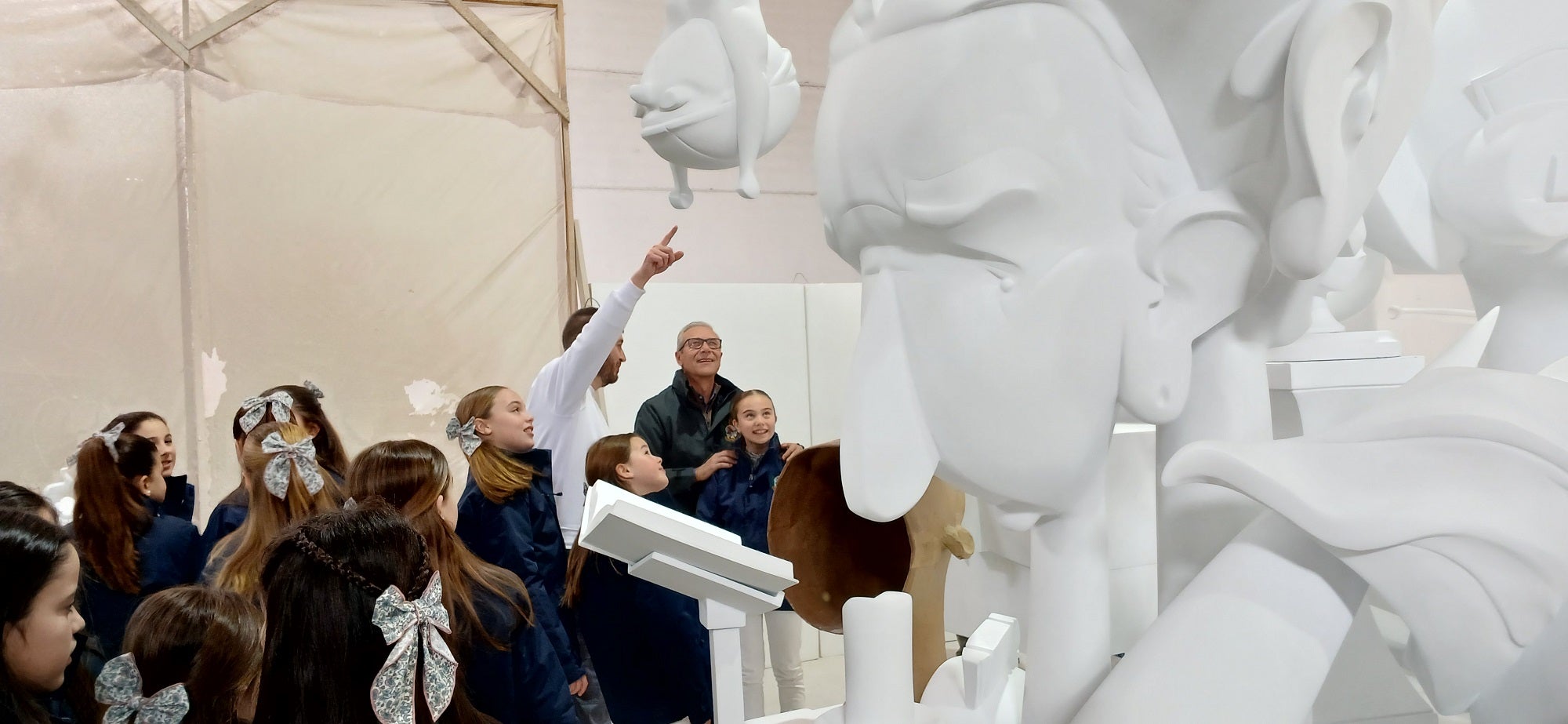 Imagen secundaria 1 - Arriba, el monumento fallero sin pintar. Sobre estas líneas, la fallera mayor infantil y las niñas que conforman la corte de honor, pendientes de las explicaciones del artista José Gallego.