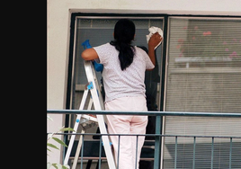 Una trabajadora limpia una ventana.