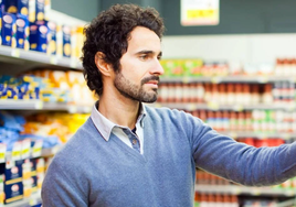 Un hombre revisa la etiqueta de uno de los alimentos en un supermercado.