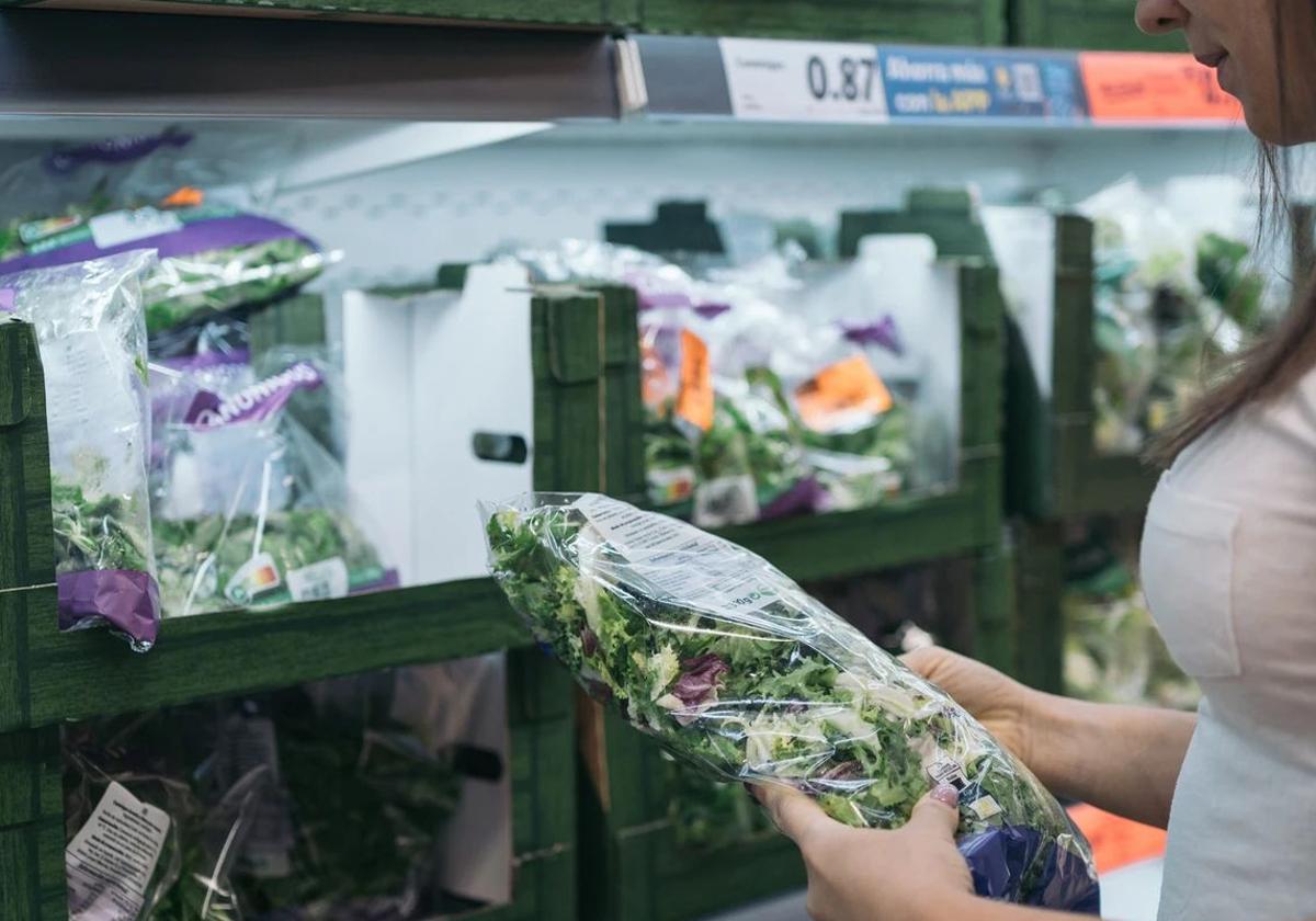 Una mujer compra lechuga en bolsa.