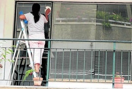 Una empleada de hogar limpia los cristales de una vivienda, en una imagen de archivo.