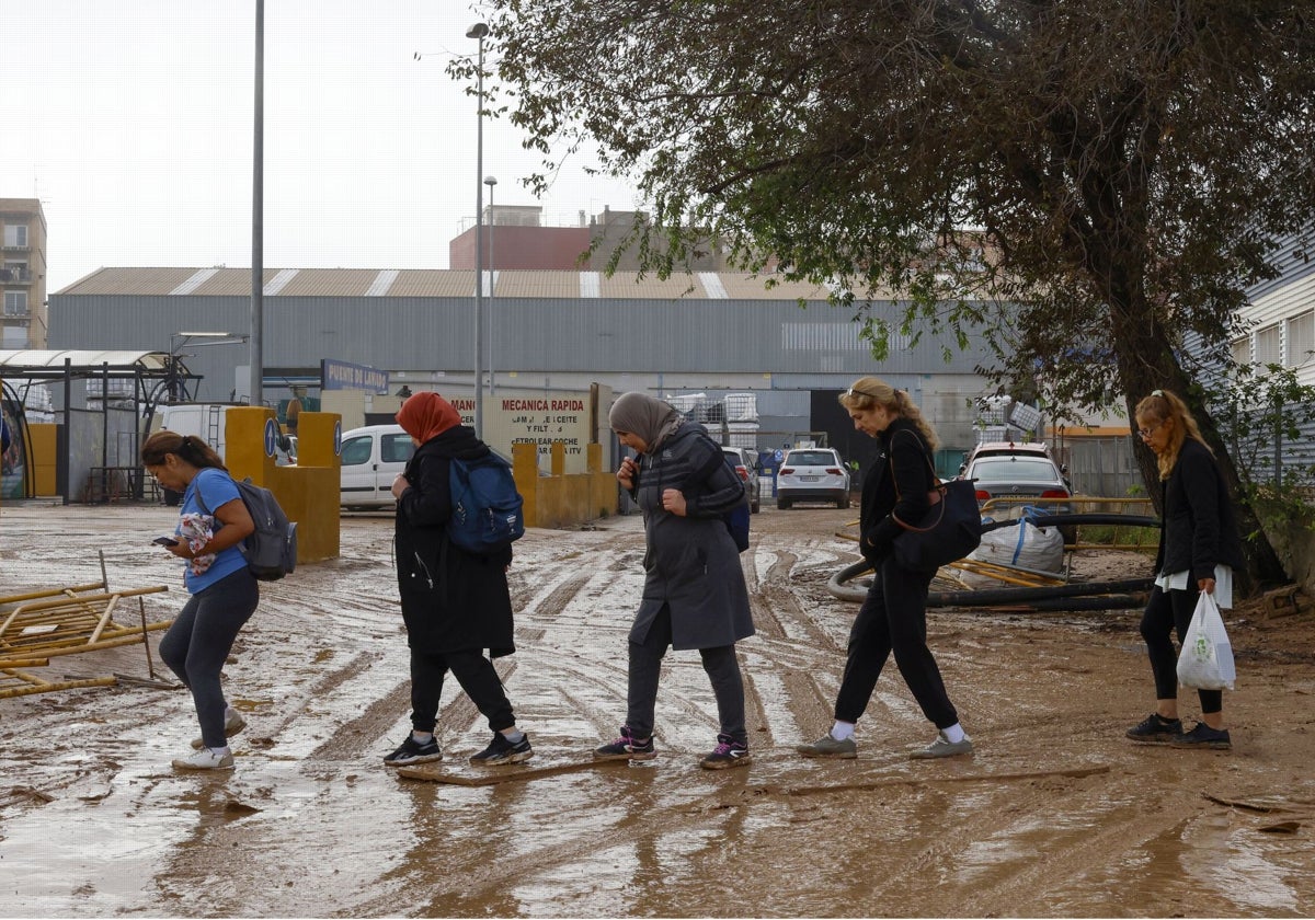 Un grupo de mujeres migrantes pasea por una zona afectada por la dana.