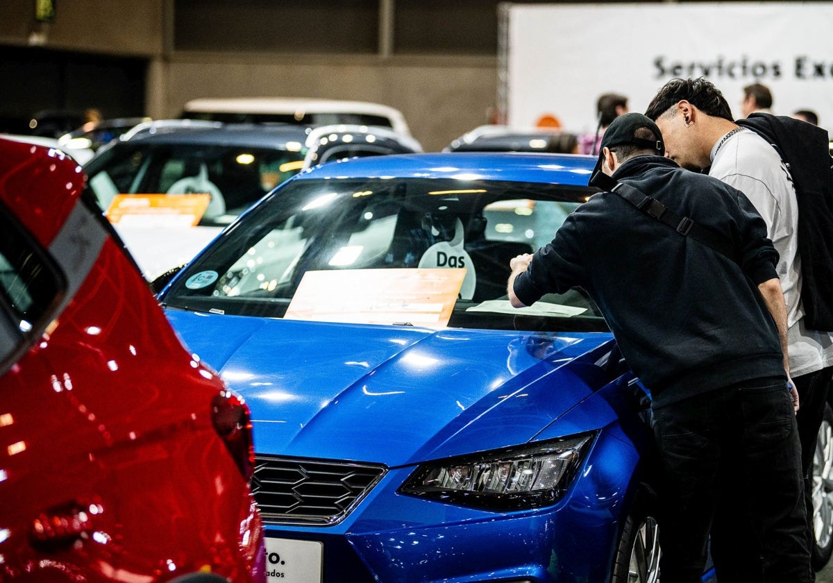 Dos compradores revisan el precio de un vehículo en la feria del automóvil.