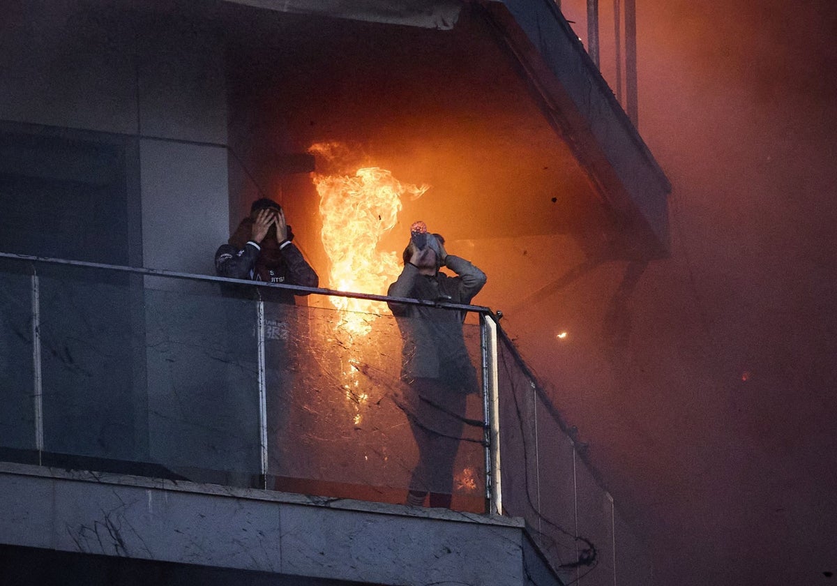 Ammar se lleva las manos a la cabeza mientras Sara bebe agua, en el balcón, rodeados por las llamas del incendio en Campanar.