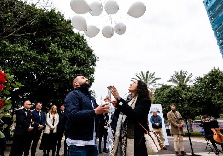 Dos asistentes al acto por las víctimas sueltan diez globos blancos en memoria de los diez fallecidos, junto al edificio siniestrado en Campanar.