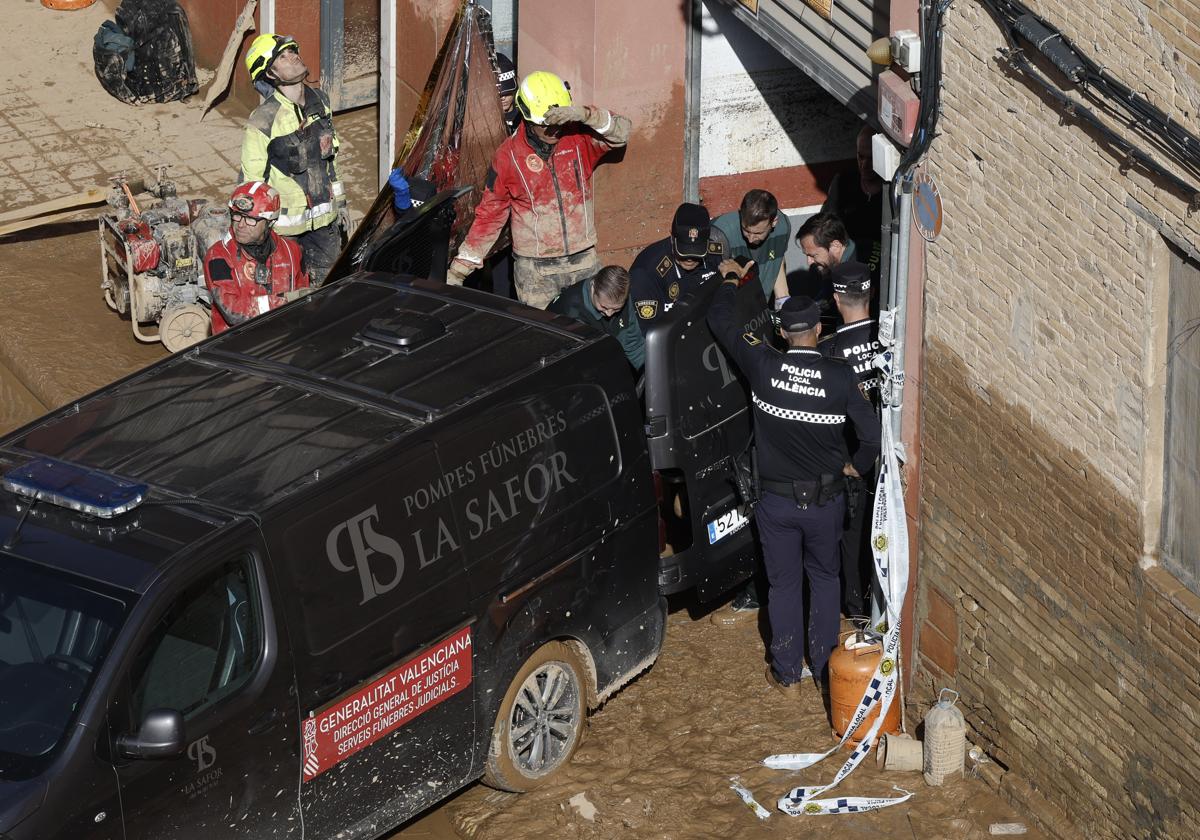 Policías, bomberos y personal del retén fúnebre, en el garaje de La Torre en el que murieron siete vecinos.