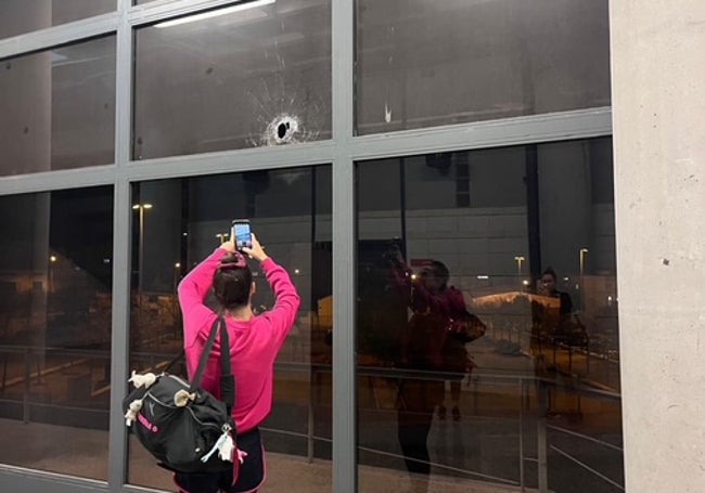 Un joven fotografía con su móvil el orificio redondo que causó el artefacto pirotécnico.