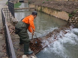Un operario limpial las rejas del río Sants a su paso por el casco urbano.