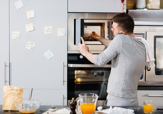 Un hombre calienta su plato en un microondas, imagen de recurso.