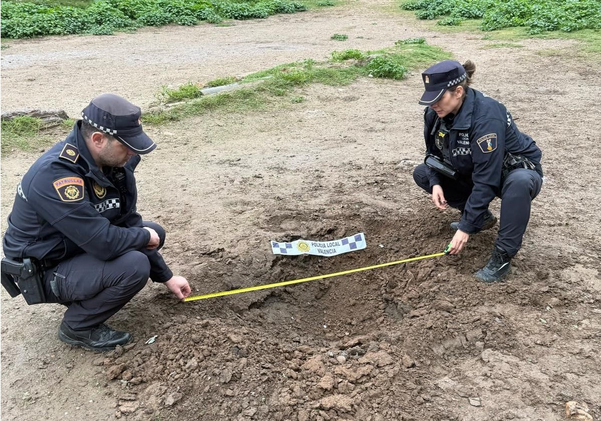 Imagen principal - Unos policías miden el agujero provocado por el petardo.