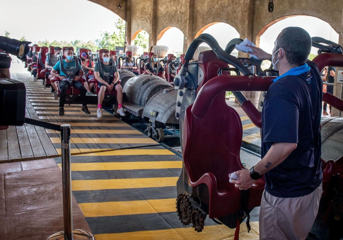 Un trabajador de PortAventura da instrucciones a los visitantes en una montaña rusa de PortAventura World.