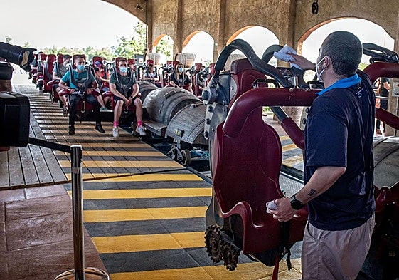 Un trabajador de PortAventura da instrucciones a los visitantes en una montaña rusa.