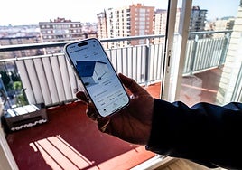 Una persona que se ha puesto placas solares autoinstalables en un balcón muestra cómo funciona la aplicación móvil.